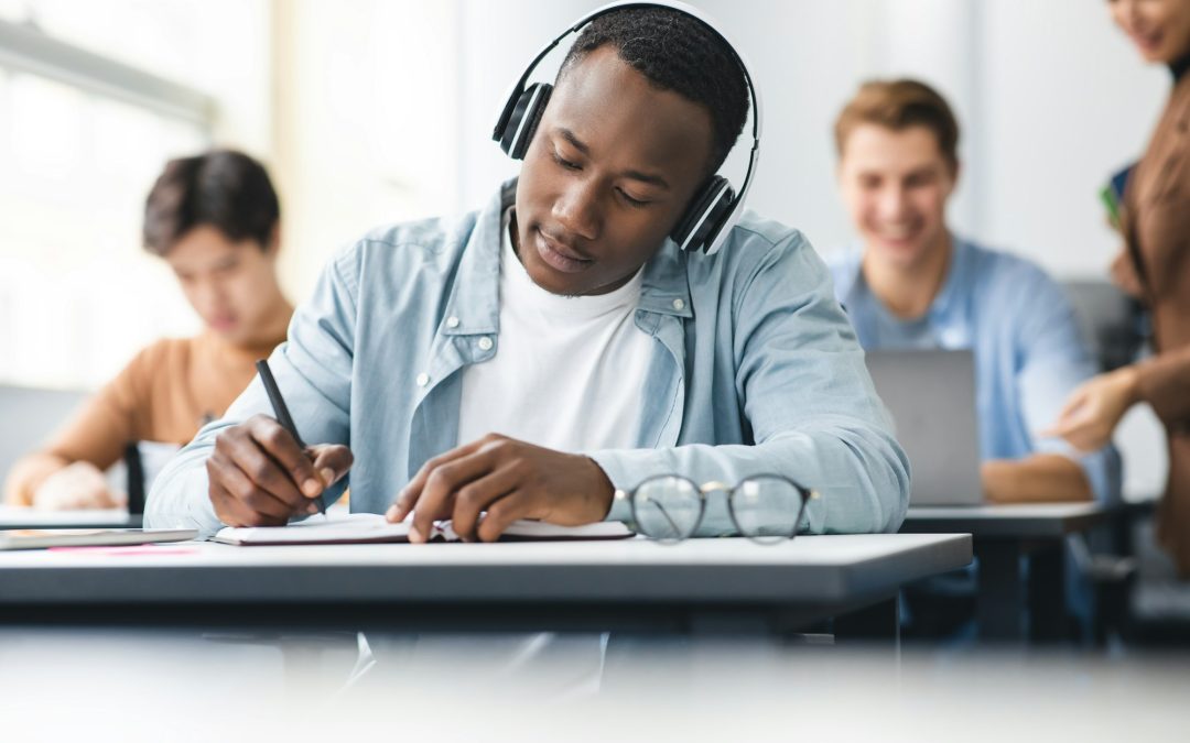 Black man sitting at desk in classroom writing exam